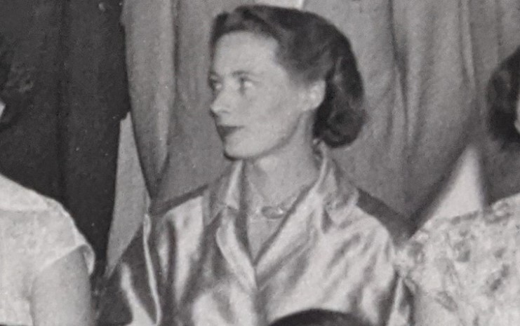Jane Osmond, a white woman in her 30s, looks to the left while wearing a gold coat