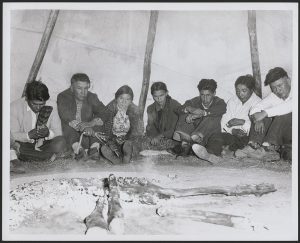 Nakoda (Stoney) and Cree men and women sit around the fire praying silently during a peyote ritual. Saskatchewan, Canada, October 1956.