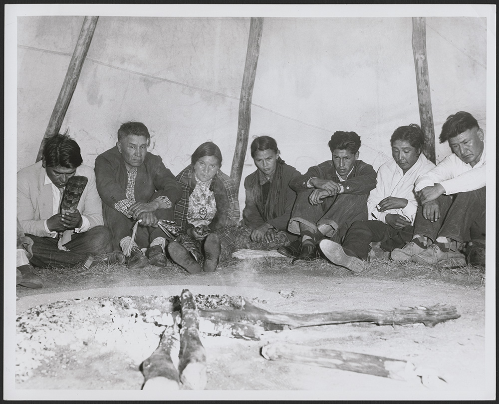 Nakoda (Stoney) and Cree men and women sit around the fire praying silently during a peyote ritual. Saskatchewan, Canada, October 1956. 