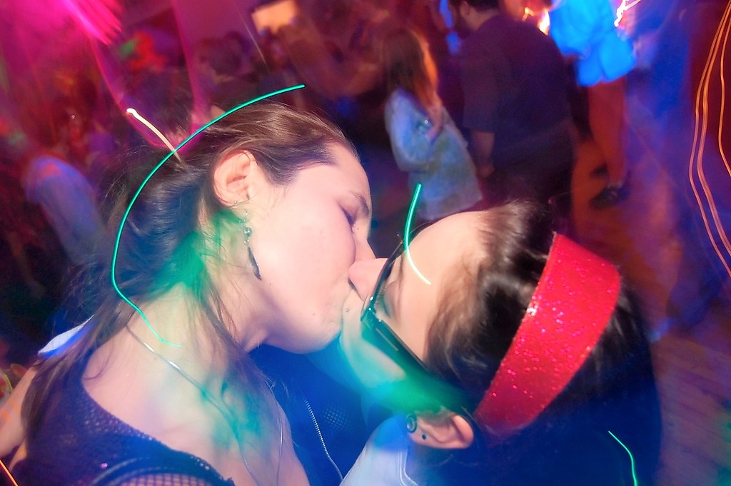 Psychedelics and pleasure: Two young white women kiss at a psychedelic rave