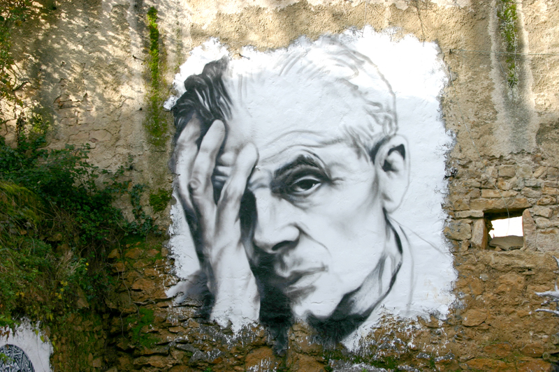 A mural of Aldous Huxley looking weary painted on an old stone wall