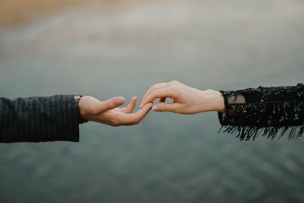 Two white feminine hands reach out to touch each other. 