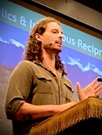 Chacruna member, white man with long brown hair, speaking at conference.