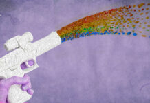 The Psychedelic Path to Resilience: Queer Activists and Collective Liberation A graphic of a pink hand holding a white gun shooting a glitter rainbow against a pink backdrop that represents queer activism and psychedelics intertwining